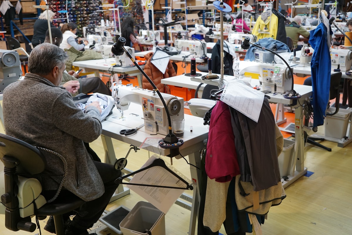 Clothing manufacturing factory floor showing workers assembling garments in an apparel production facility
