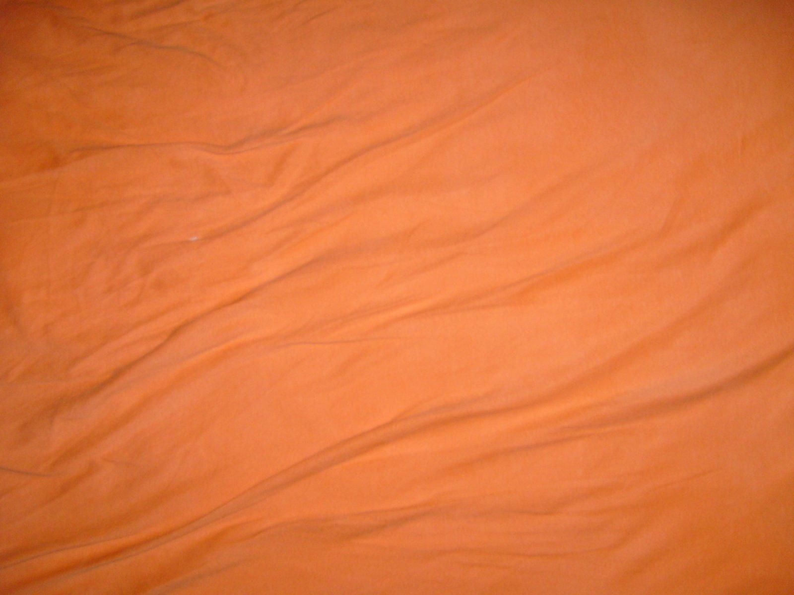Close-up view of orange woven fabric texture showing textile material pattern and GSM weight