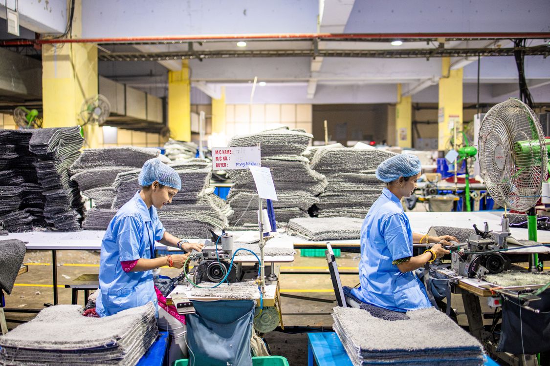 Factory workers operating sewing machines on a garment production line showing labor cost factors in clothing manufacturing