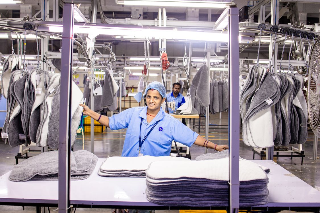 Textile factory worker performing quality control inspection on fabric in a garment manufacturing facility