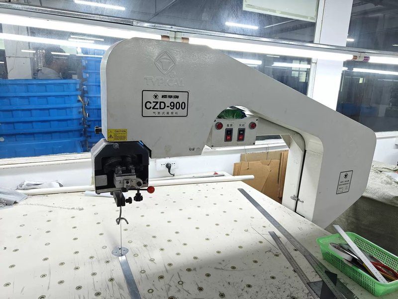 Automated pneumatic fabric cutting machine on a garment factory cutting table