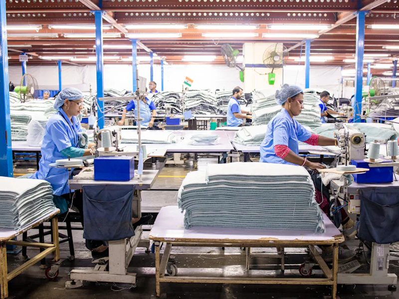 Cut fabric panels stacked at sewing stations in a cut and sew garment factory