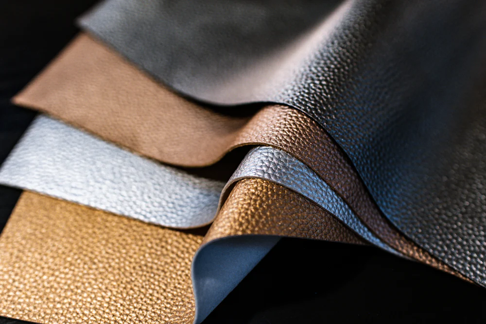 Textured fabric and leather swatches fanned out for material selection during the garment sampling process