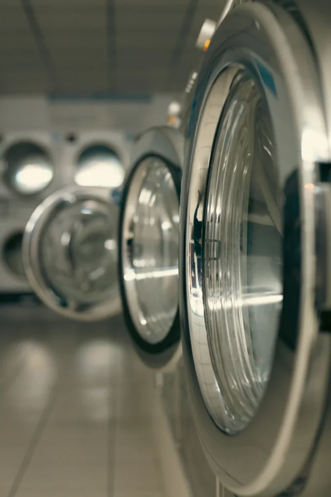 Row of industrial washing machines used for garment wash finishing after cut-and-sew production