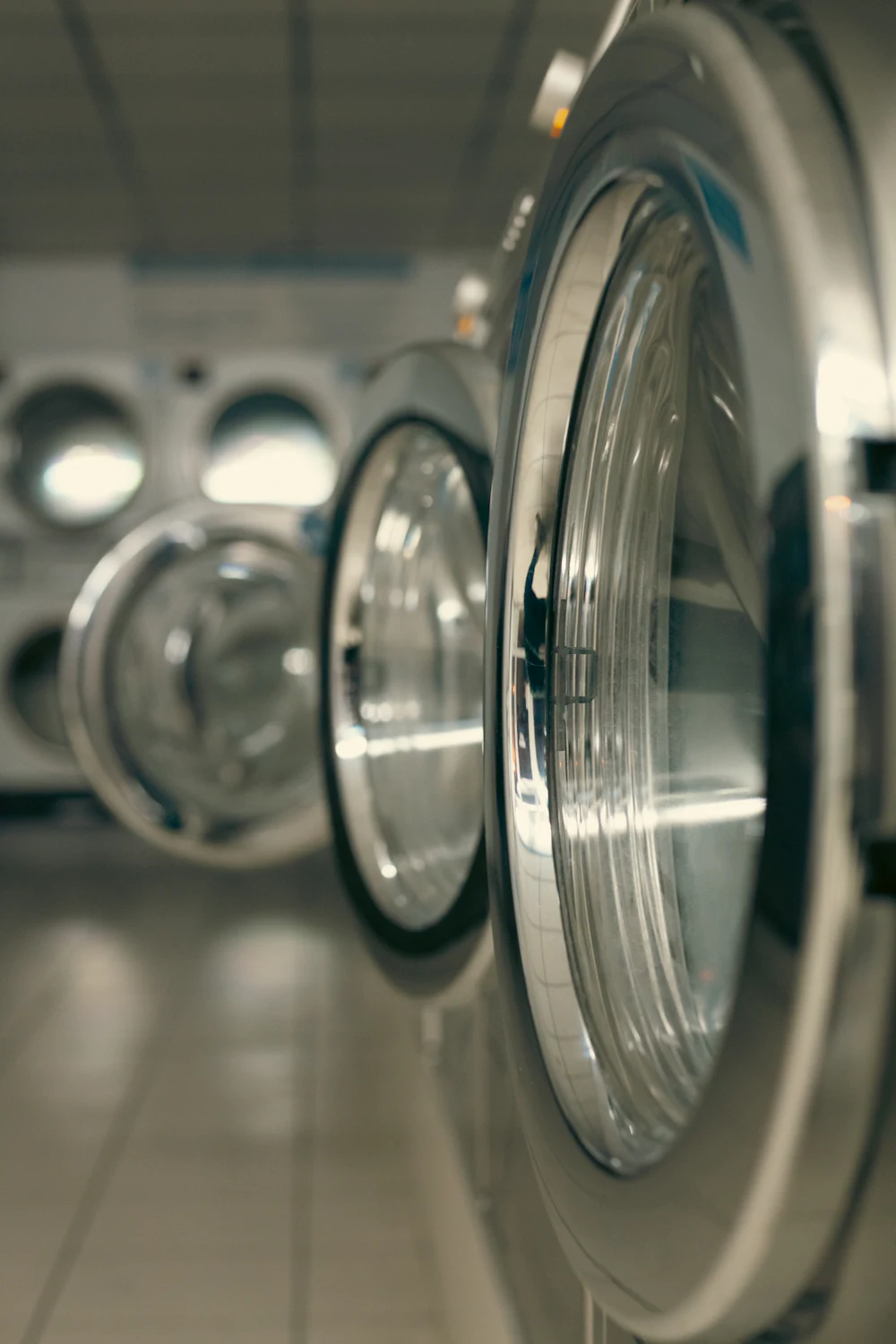 Row of industrial washing machines used for garment wash finishing after cut-and-sew production
