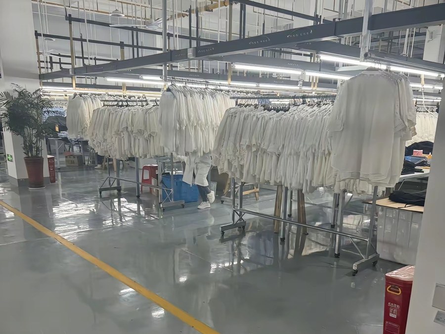 Rails of finished white garments on the production floor at a healthcare uniform manufacturer