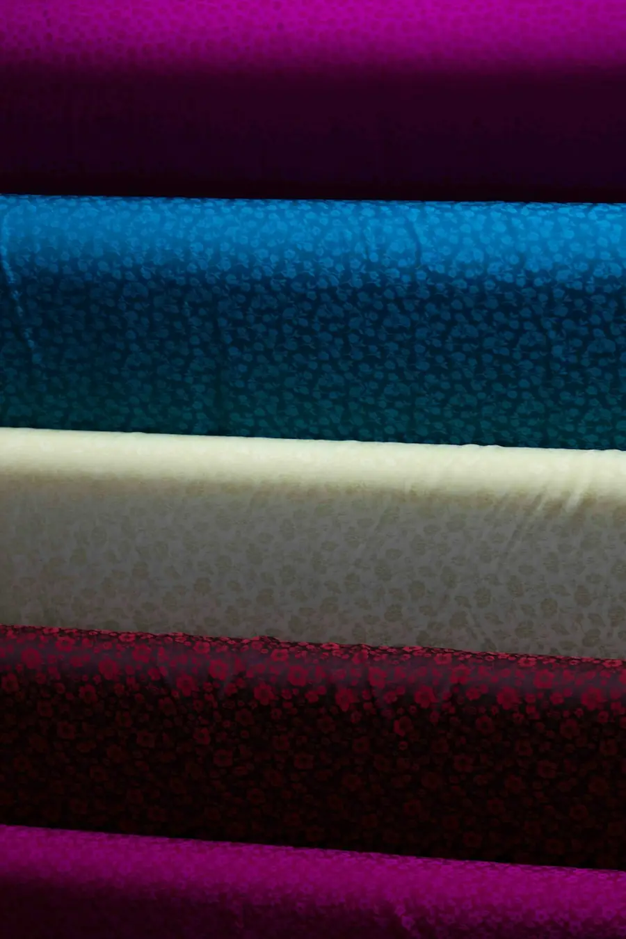 Stacked fabric rolls in multiple colorways illustrating per-colorway minimum order quantity clothing math