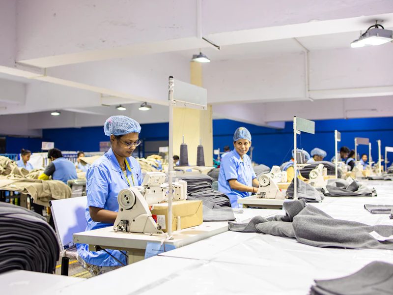 Garment workers sewing on an active clothing factory production line