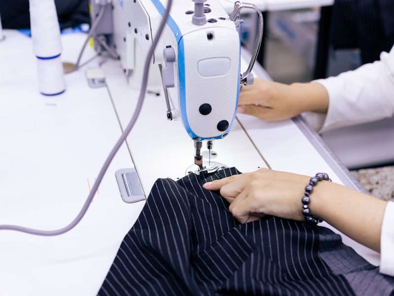 Hands operating an industrial sewing machine during quality control stitching inspection