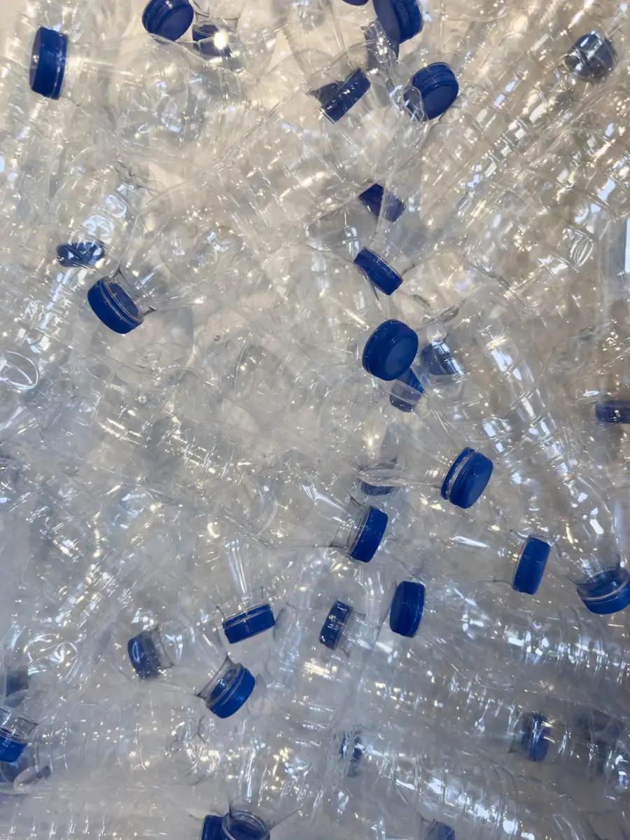 Baled clear PET plastic bottles collected for processing into rPET fiber by a recycled fabric clothing manufacturer
