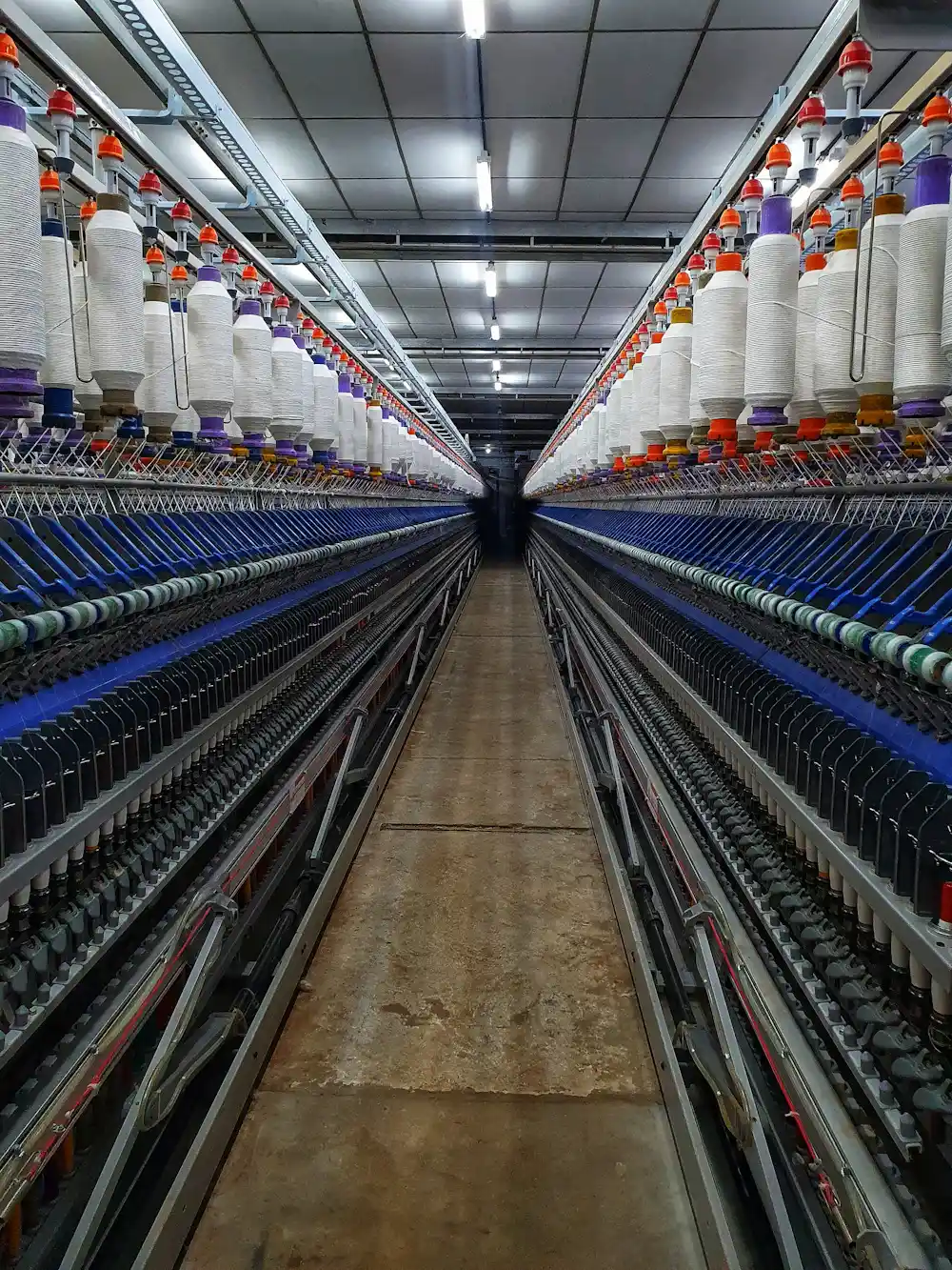 Rows of yarn spools at a spinning mill supplying a recycled fabric clothing manufacturer