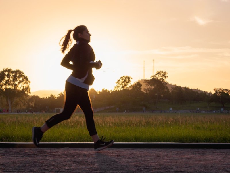 Silhouette of a runner in athletic leggings and jacket at sunset