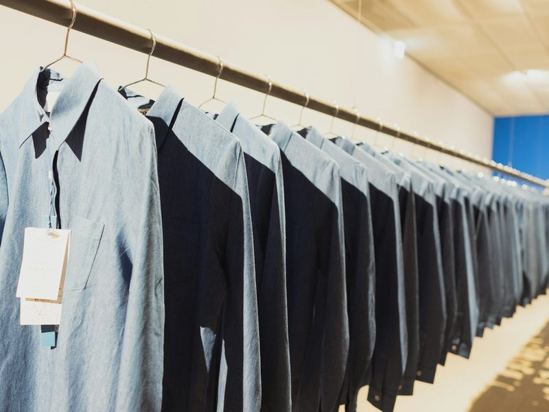 Row of identical chambray uniform shirts hanging on a rail