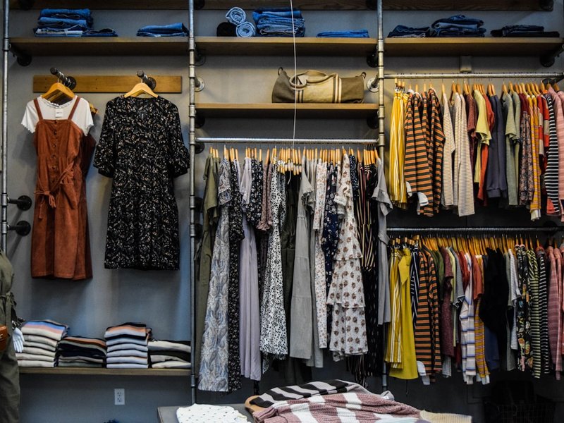 Boutique display of womens dresses and tops on hangers and shelves