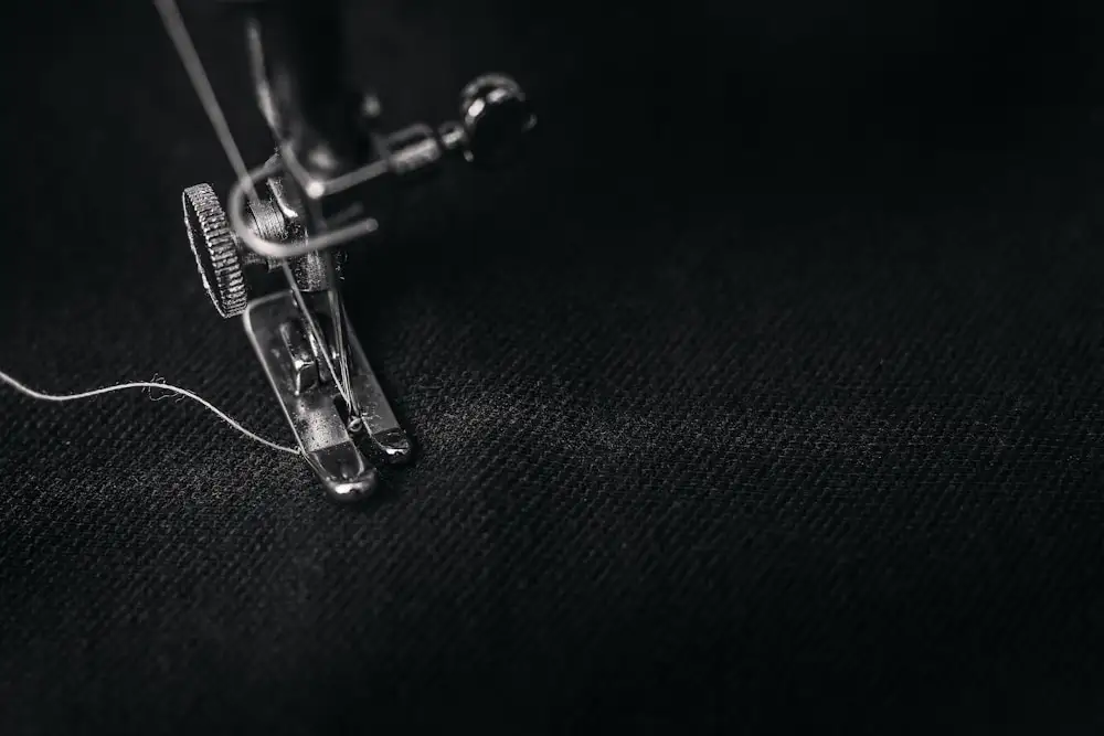 Sewing machine needle and thread stitching into fabric, illustrating the physical stitch path an embroidery digitizer builds from artwork