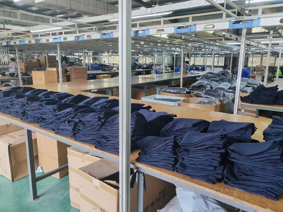Folded navy garments staged on production tables on the PRP Apparel factory floor