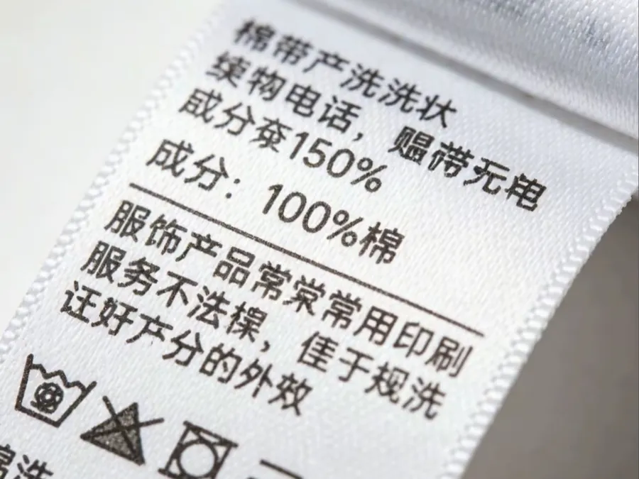 Printed care label showing wash symbols and fiber content, meeting clothing care label requirements