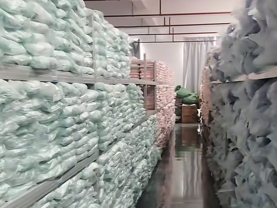 Aisle of plastic-wrapped fabric bolts stacked in the PRP Apparel warehouse