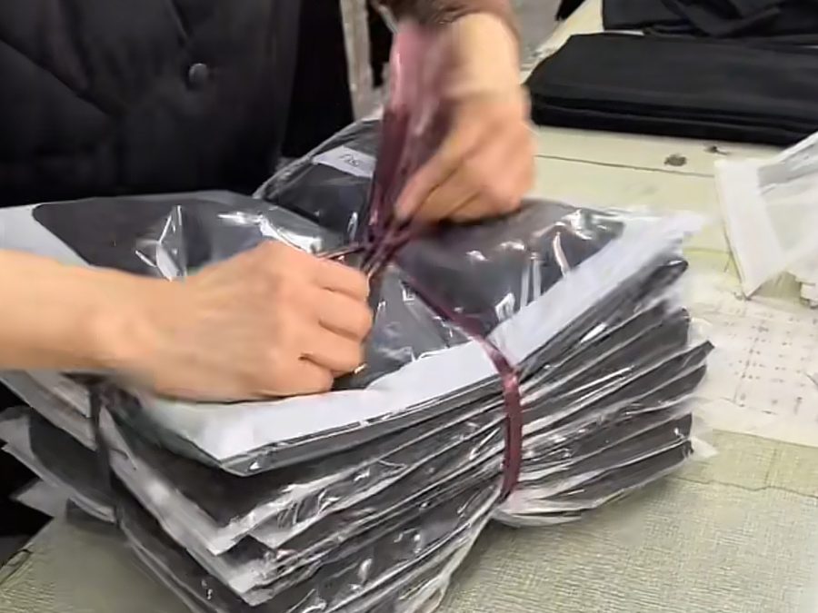 Worker bundling poly-bagged garments during the packaging and labeling process