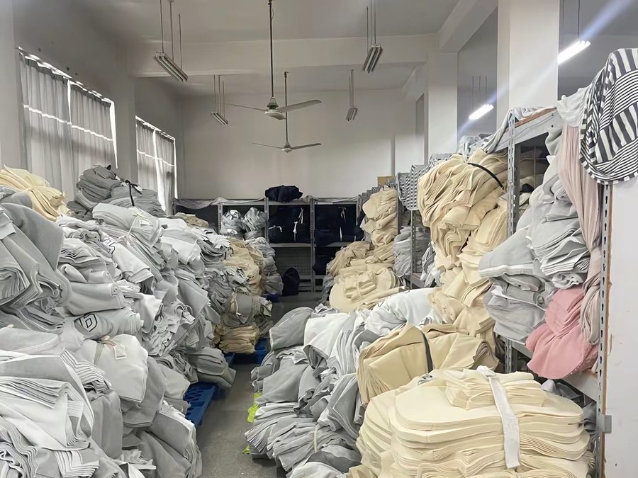 Shelves of cut fabric held on file for corporate uniform reorder matching