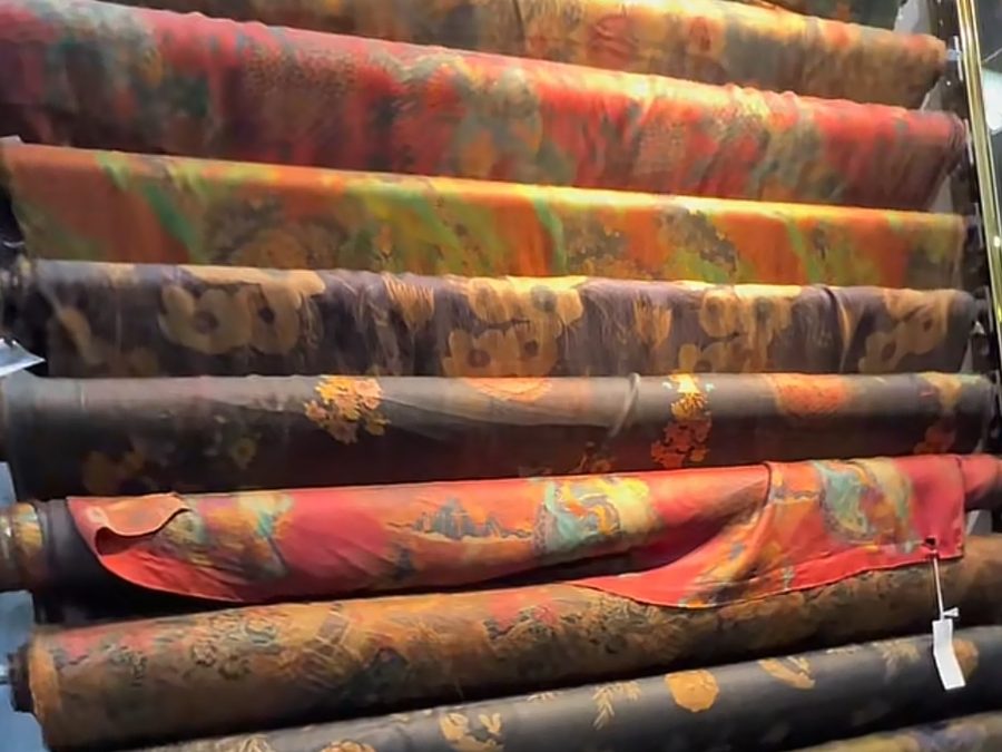 Rolls of colorful patterned fabric stacked on a textile mill rack