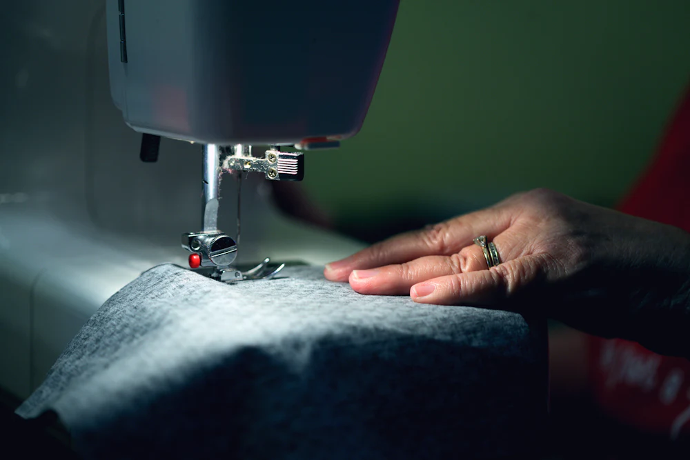 Factory sewing machine stitching fabric after shrinkage testing confirms dimensional stability