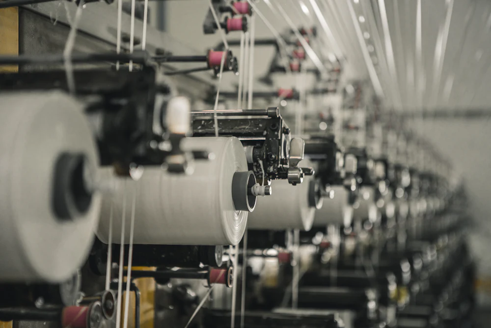 Yarn spools on a textile mill production line supplying fabric for shrinkage testing