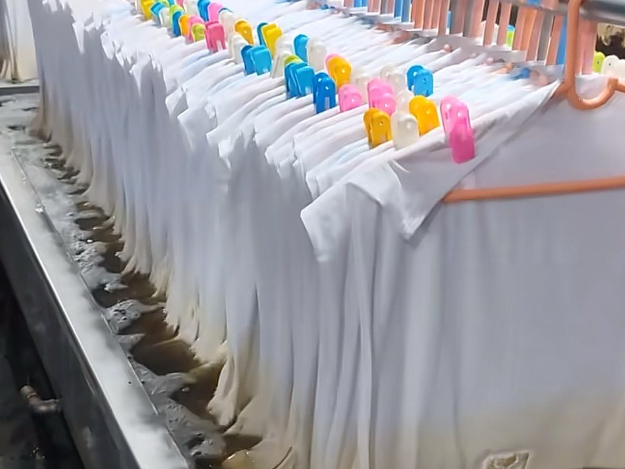 T-shirts moving through a wash and dye line at PRP Apparel's production facility