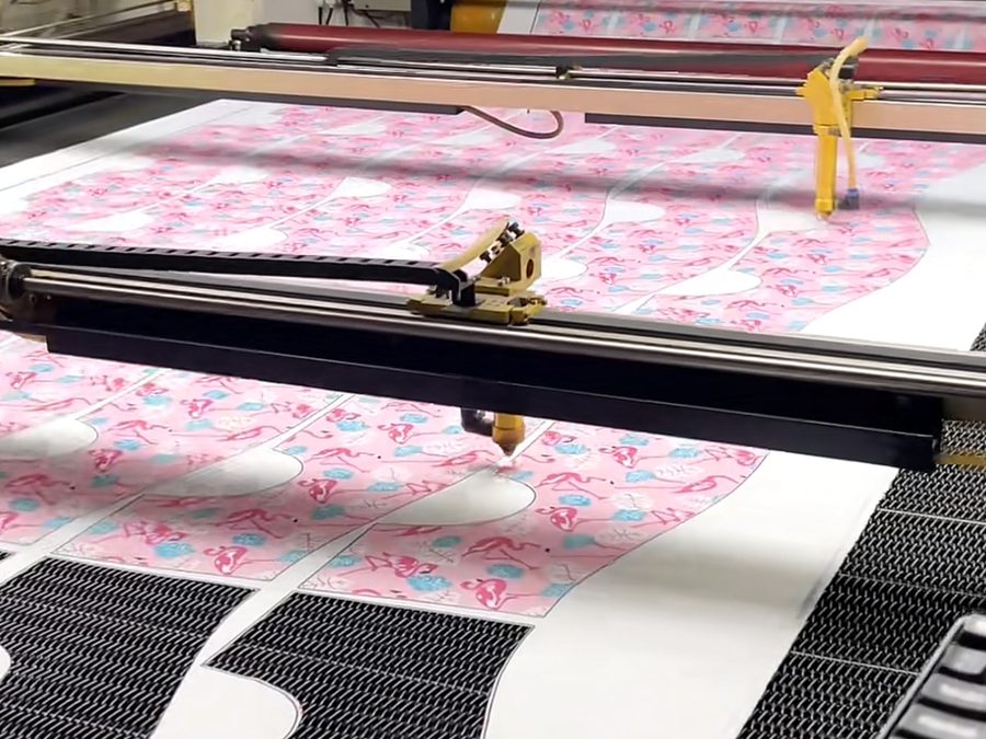 Large-format CNC laser cutting machine cutting printed fabric panels on a roll-fed cutting table