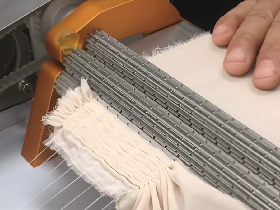 Natural linen-toned fabric edge being finished on a fringing machine