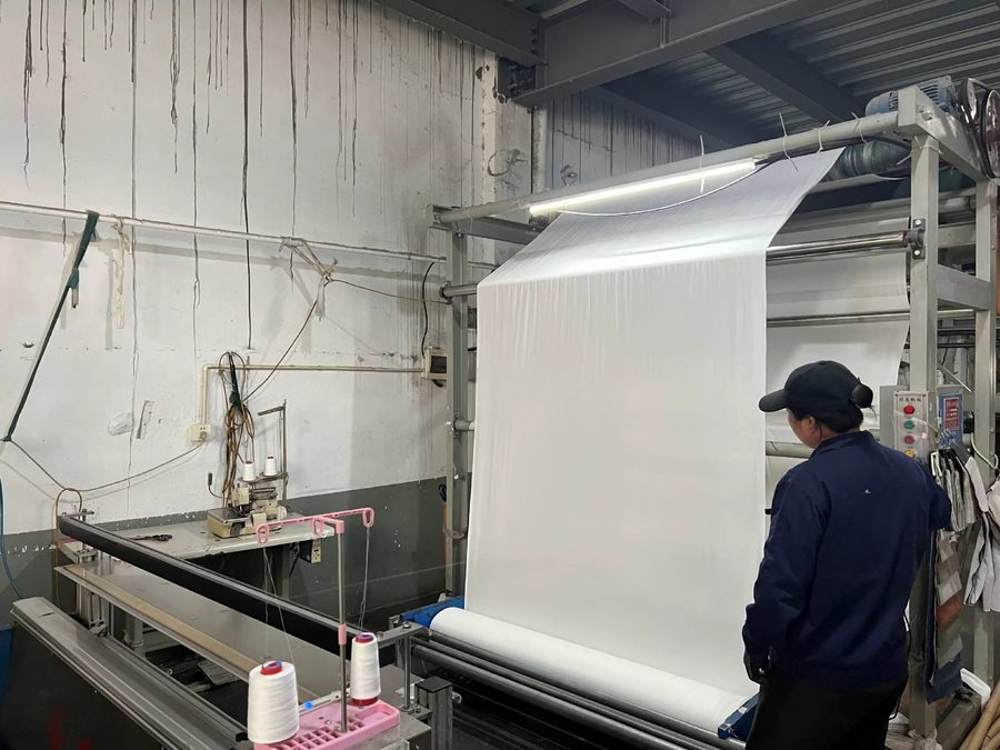 Smooth technical nylon fabric being rolled off the finishing machine