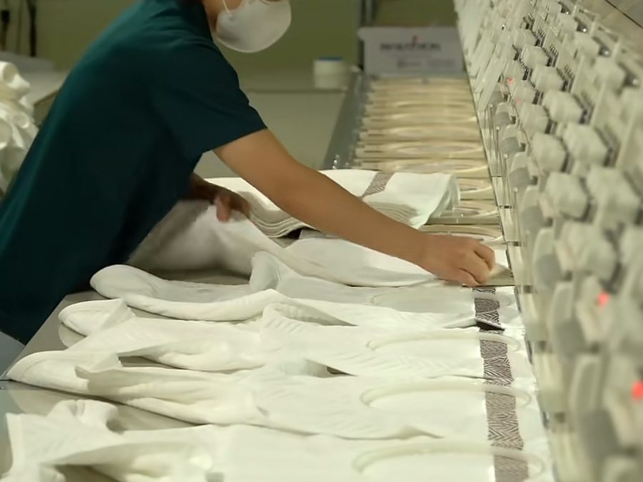 Worker inspecting finished knit fabric during quality control at a clothing manufacturer