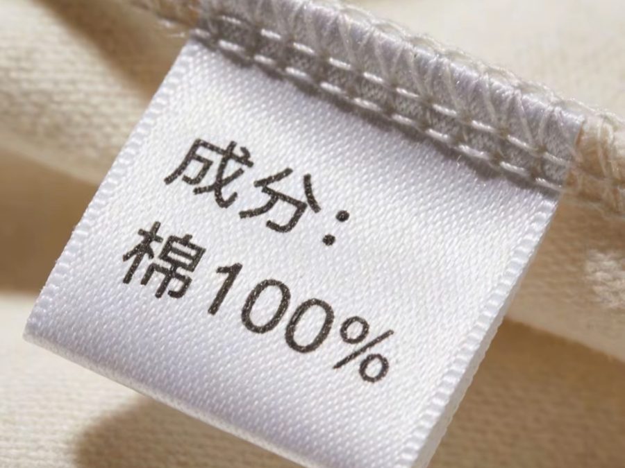 Fabric composition label reading 100% cotton sewn into a school uniform garment seam