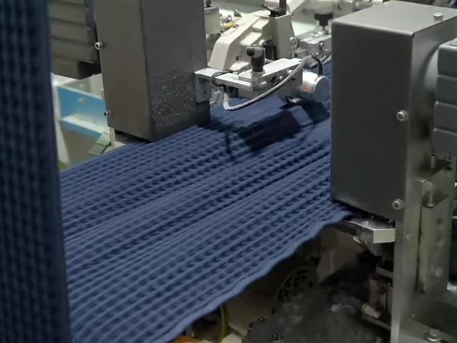 Technical knit fabric running through finishing machinery for sportswear production