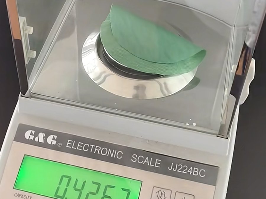 Fabric swatch weighed on a digital GSM scale to verify weight before a startup brand's first production run