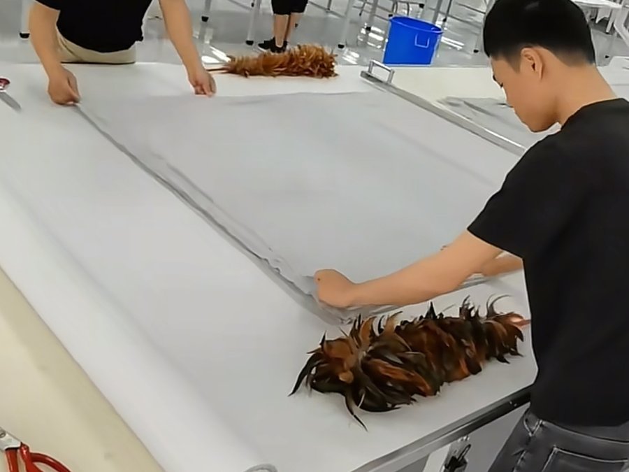 Two workers hand-cutting a small-batch fabric roll on a cutting table for a startup brand's first order
