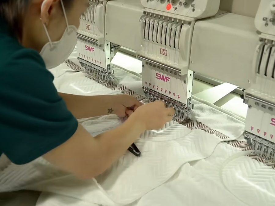 Multi-head embroidery machine stitching a heavyweight herringbone panel for streetwear branding