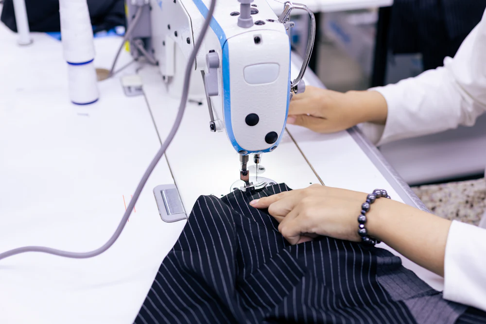 Factory sewing machine operator cutting and stitching fabric at a yoga pants manufacturer