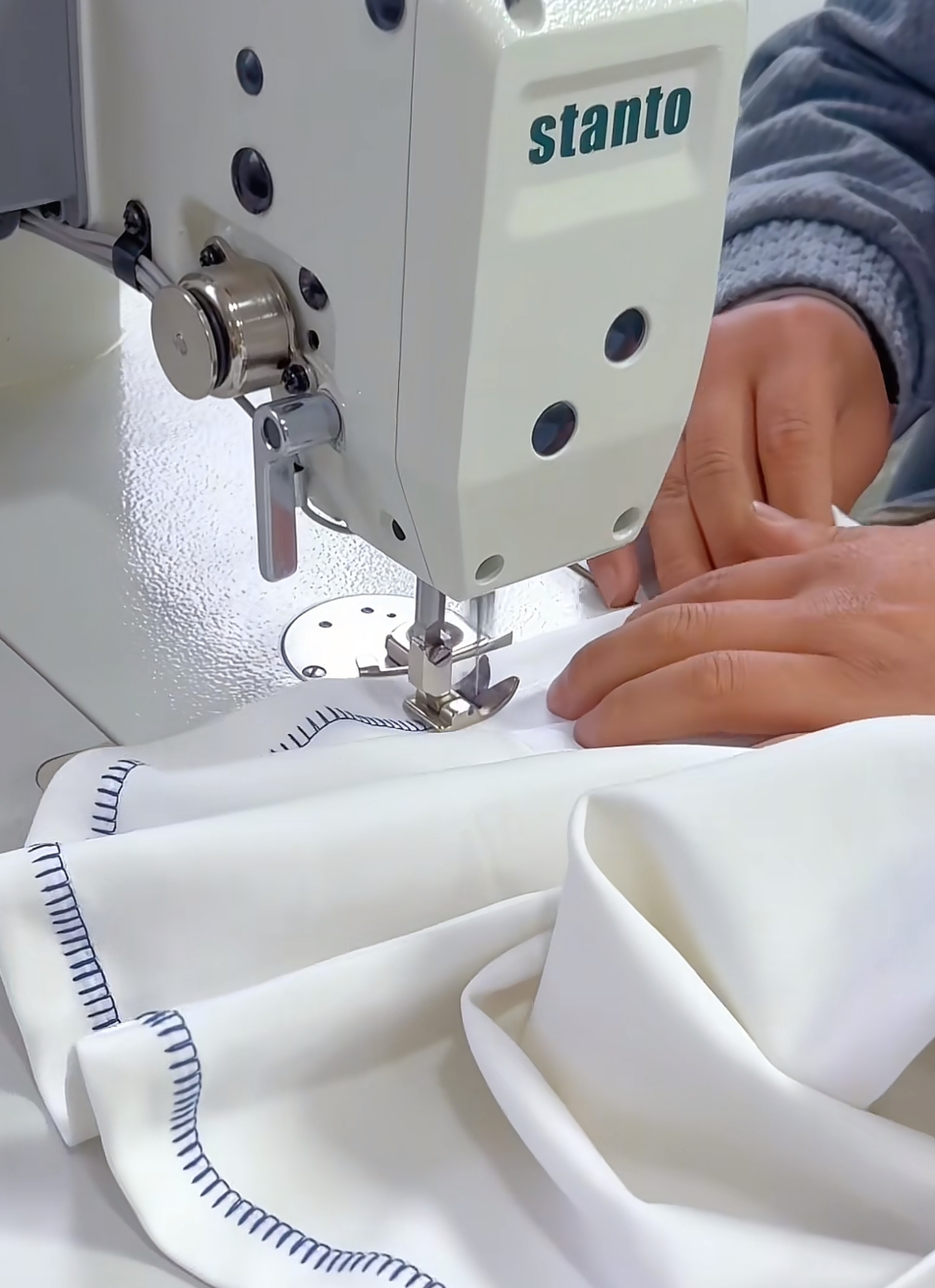 Cotton fabric being gathered and stitched with a scalloped edge finish on an industrial sewing machine