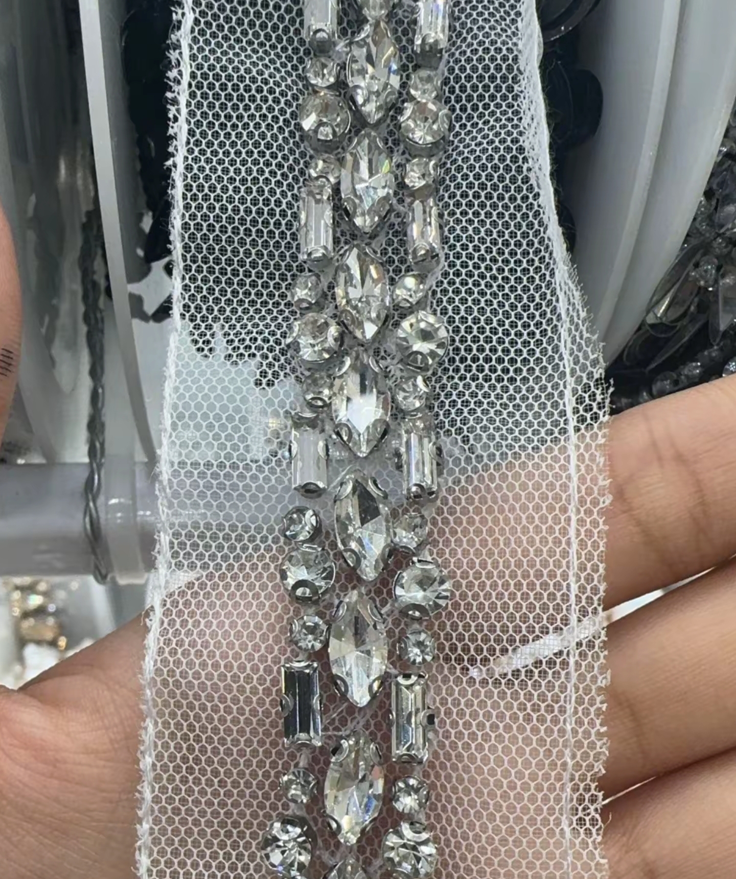 Close-up of a clear rhinestone chain trim with baguette and round-cut stones set in a metal channel