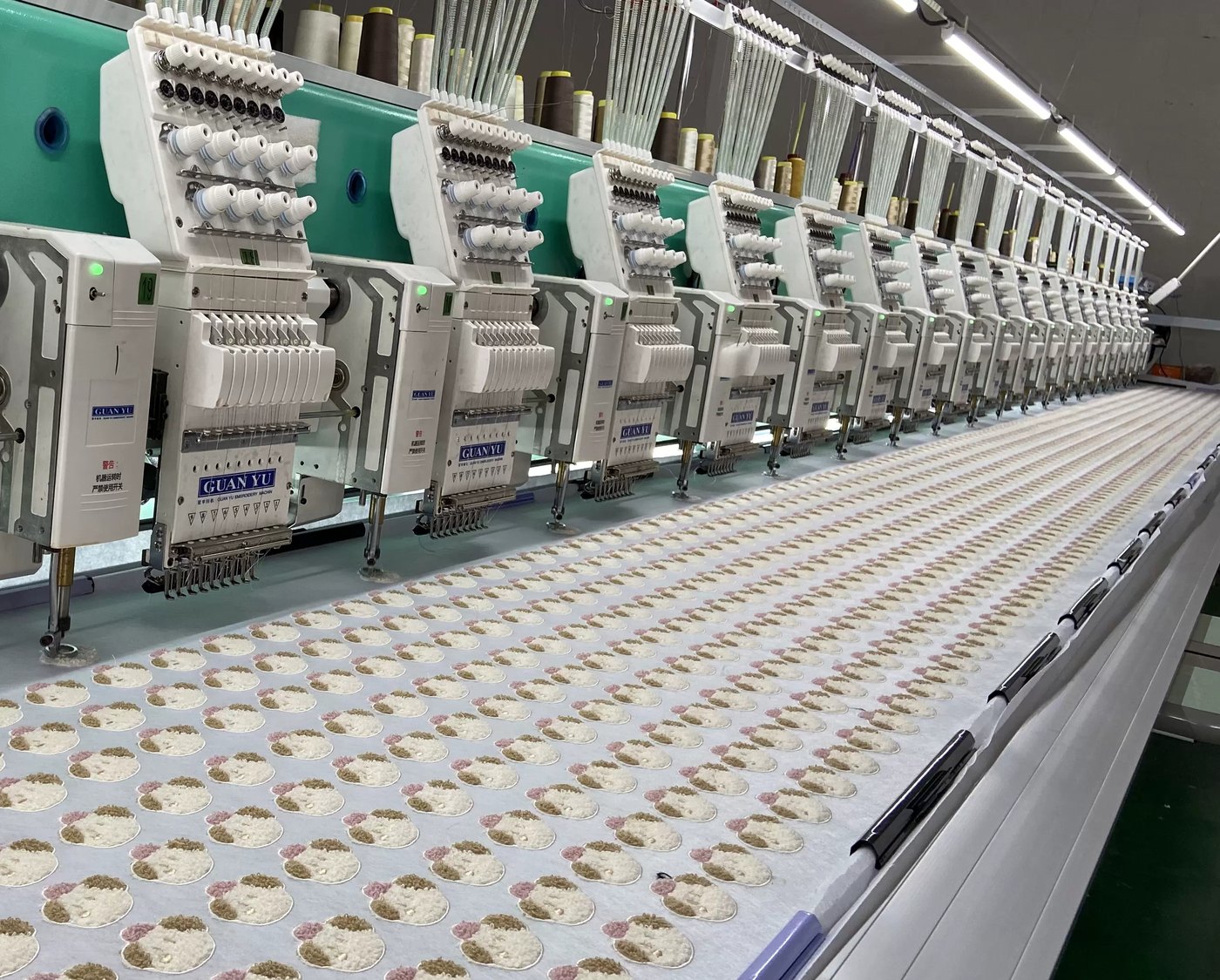 A long multi-head embroidery line stitching rows of motifs across a fabric bed
