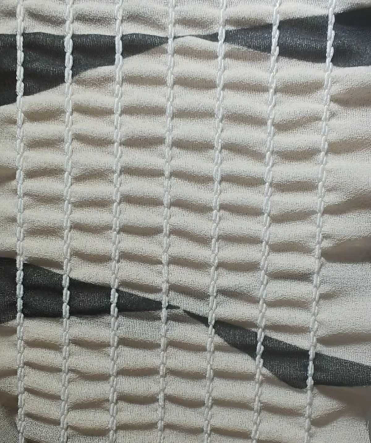 Close-up of parallel shirring stitch rows gathering printed fabric into even ridges