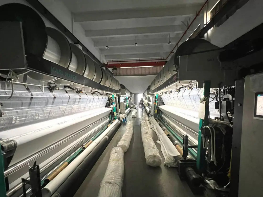 Fabric rolls moving through a warp-knitting line before any cutting decision is made