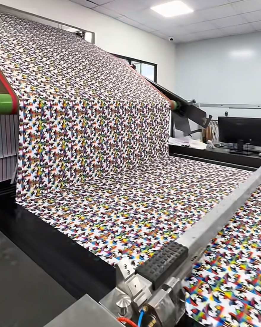 Roll of multicolour printed fabric feeding over the drum of a rotary heat press