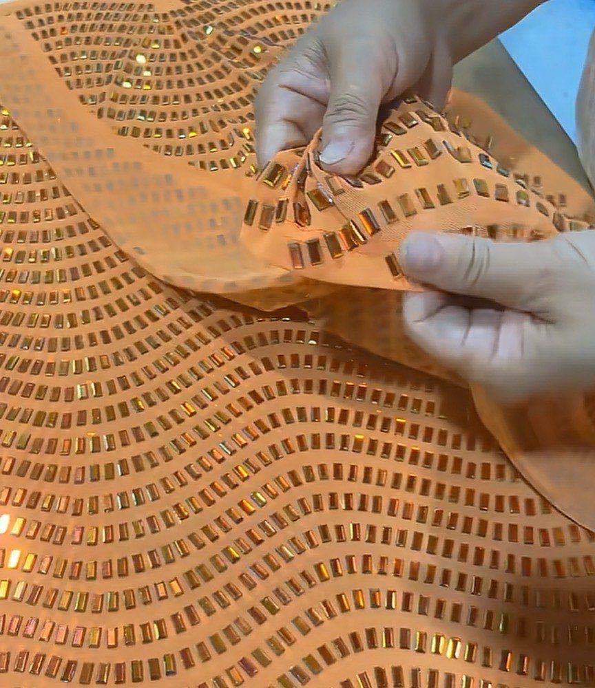 Rows of rectangular amber stones set across a light orange mesh fabric, held up by hand